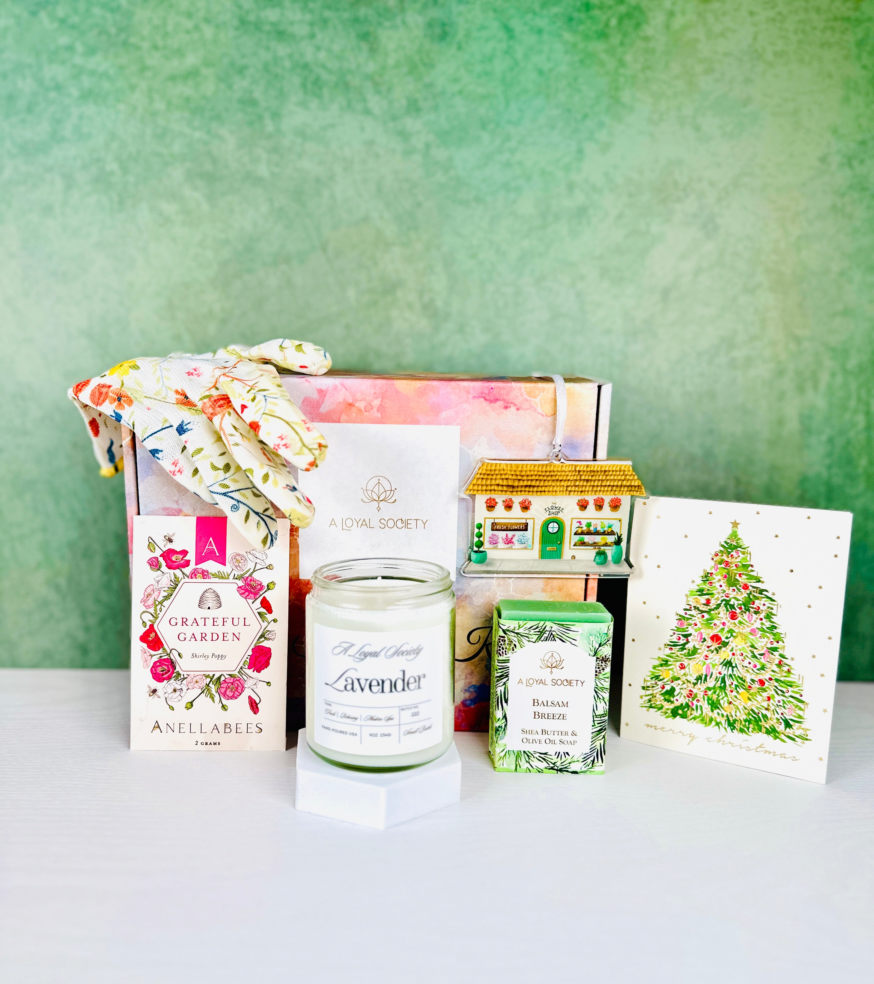 The Christmas in the Flower Garden Gifset from A Loyal Society has a garden theme and is great for gardeners and nature lovers. The gift set includes a floral-patterned gardening gloves, a scented candle, a small decorative "flower shop" themed ornament, one packet of Shirley Poppy flower seeds, a balsam scented bath soap, and an elegant Christmas tinsel tree greeting card.
