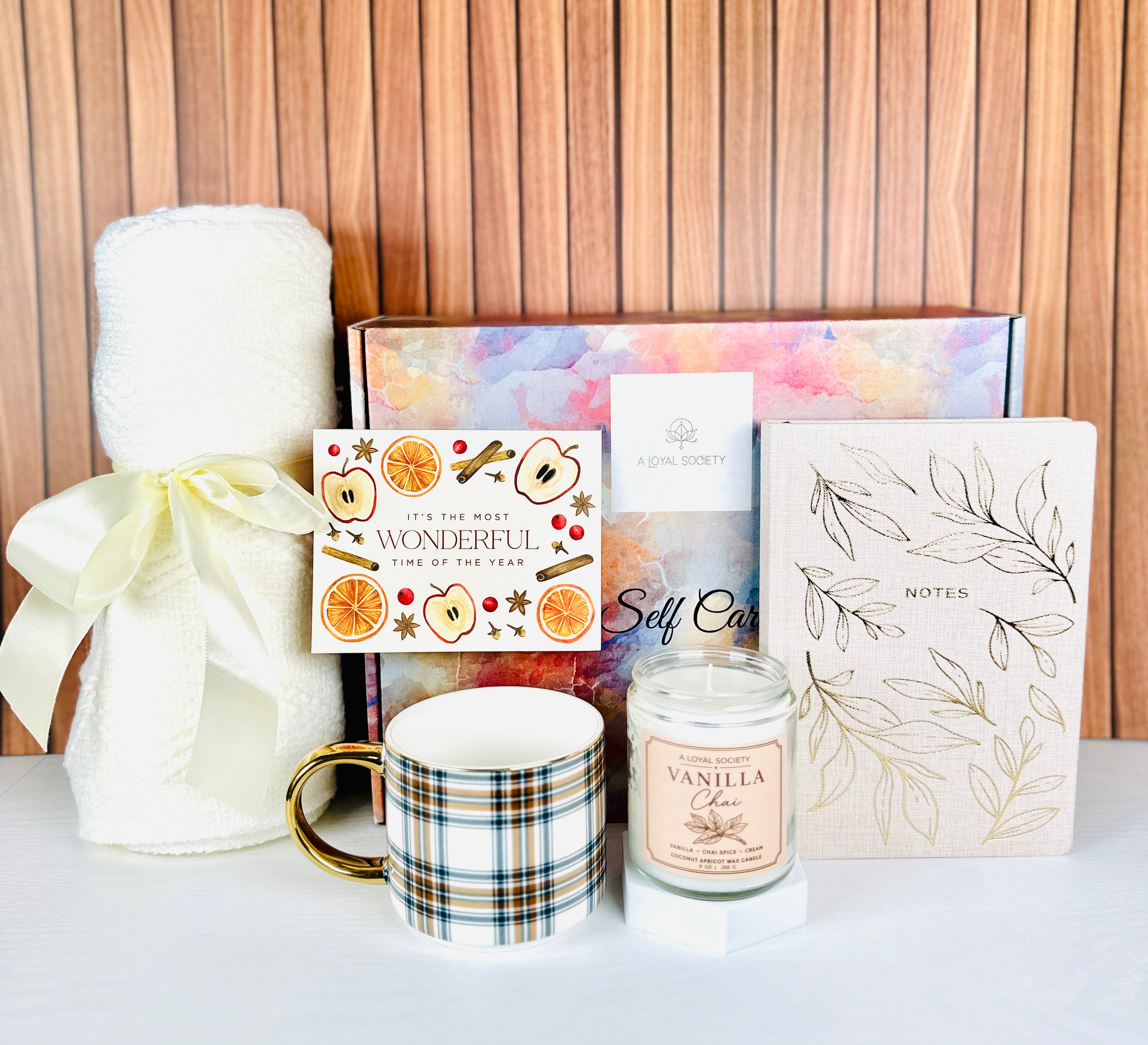 This A Loyal Society curated gift set is a beautiful way to celebrate fall birthdays, Thanksgiving and special occasions . It includes a lightweight cream-colored throw blanket, a chic plaid mug with a gold tone handle, a Vanilla Chai scented candle, a gold tone embossed linen notebook and a chic "It's the most wonderful time of the year" greeting card that is blank inside for your gift message.