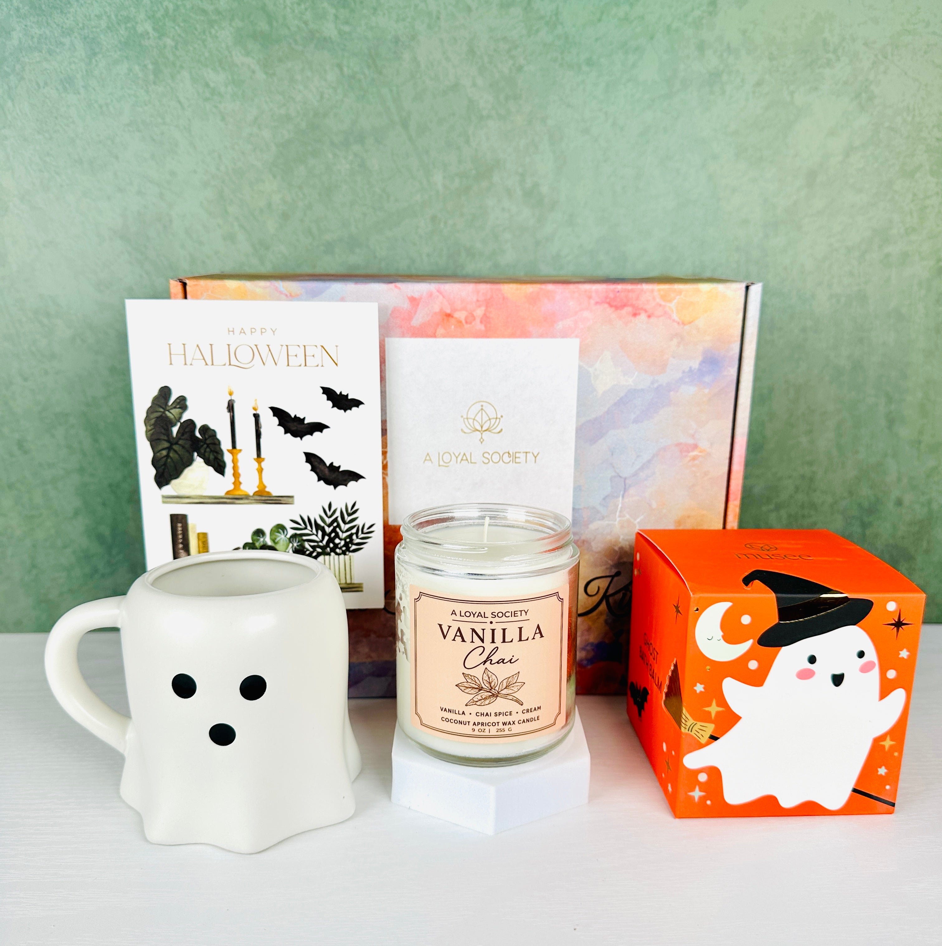 This A Loyal Society Cozy Ghost Halloween Boo Basket Gift Set features a ghost-shaped mug, a 'Vanilla Chai' scented candle from A Loyal Society, a Halloween ghost themed bath bomb that is a marshmallow scent and a blank Halloween card for your gift message.