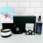 A Loyal Society Men's Christmas gift set  that has a game night theme. It a winter-themed greeting card, stainless steel dice and carrying case, a relaxing masculine scented candle, a deck of waterproof playing cards and a bottle of  cologne mist.