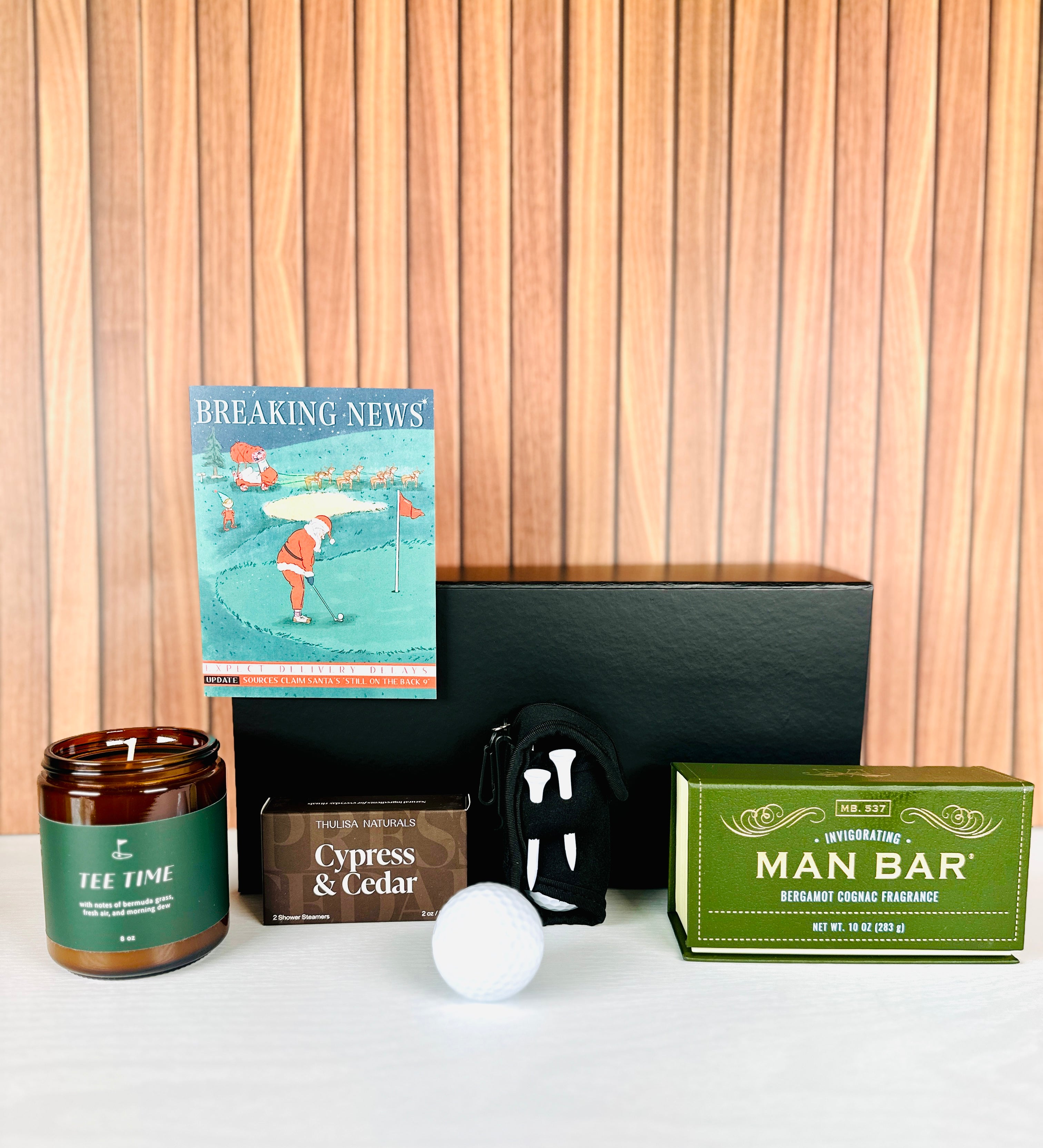 A Loyal Society Men's Christmas gift set that is a golf theme. The gift set includes 4 golf tees and 2 golf balls, along with a "tee time" scented candle. It also includes a  'Breaking News' Christmas card, a bath body bar soap and a pack of shower steamers. Great for a golf loving family member or friend!