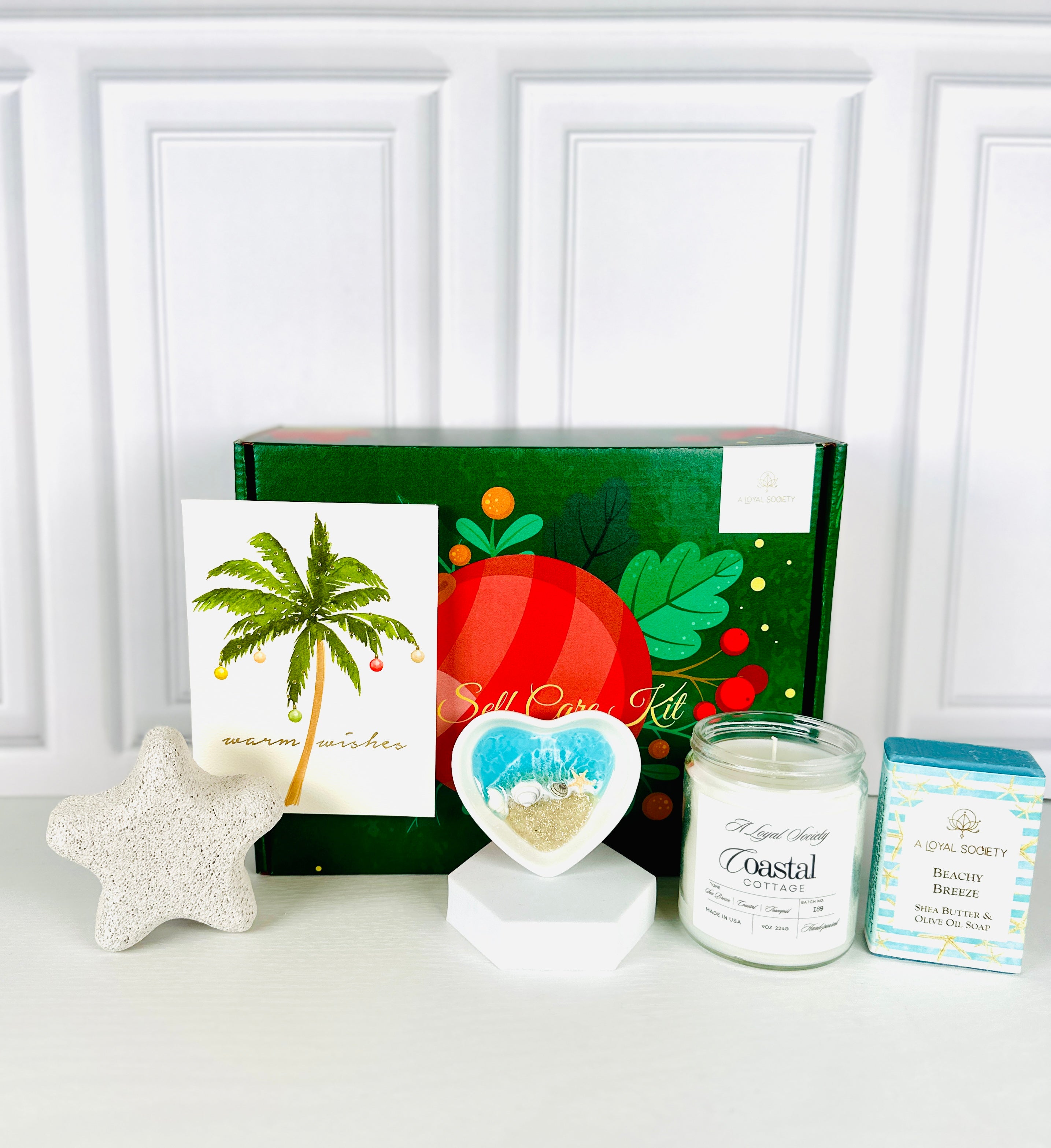 This beach themed A Loyal Society Christmas Gift Set is perfect for beach lovers or those who could use a warm weather moment during cold winter weather.  This giftset includes a beach scented candle, a beautiful artisan heart-shaped jewelry dish with real sand and blue resin, a beach breeze scented body bar soap, a starfish-shaped pumice stone for pedicures and a Warm Wishes holiday card. 